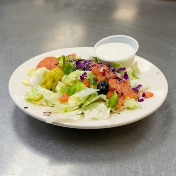 A side salad with lettuce, pepperoni, peppers, olives, and a side of ranch dressing.